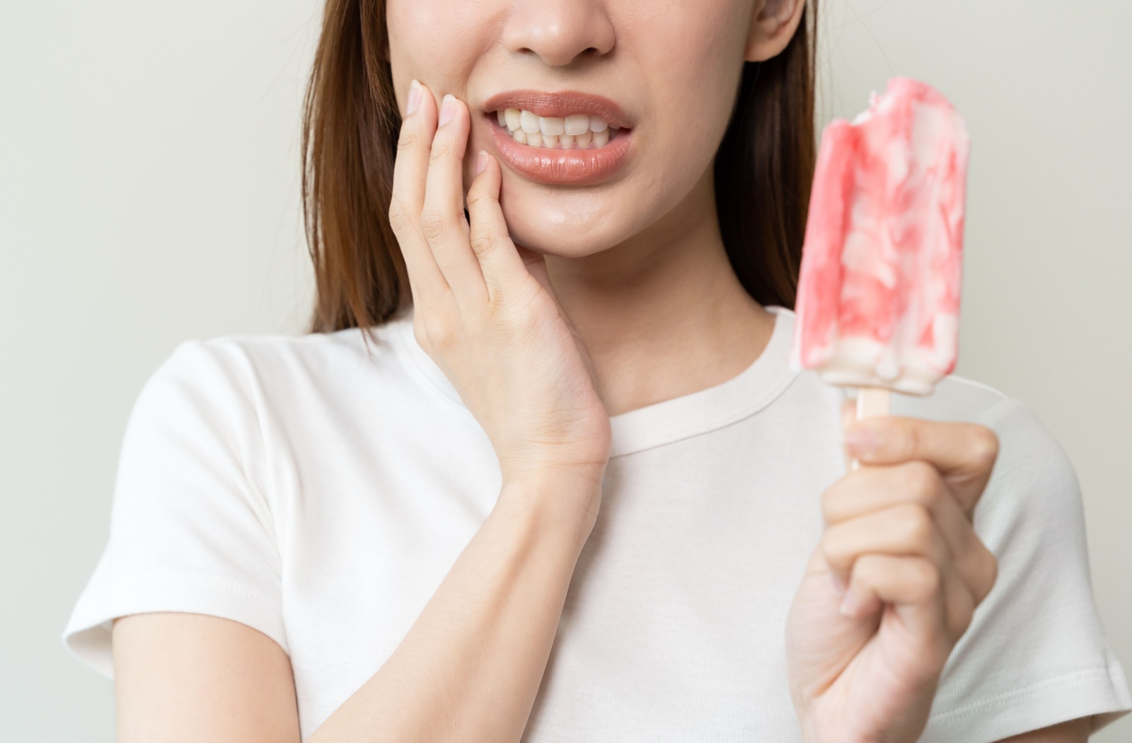 Person experiencing tooth sensitivity while eating a popsicle.