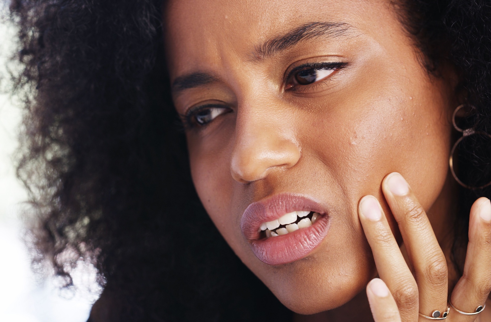 Person holding jaw with visible discomfort showing signs of TMJ-related tooth pain