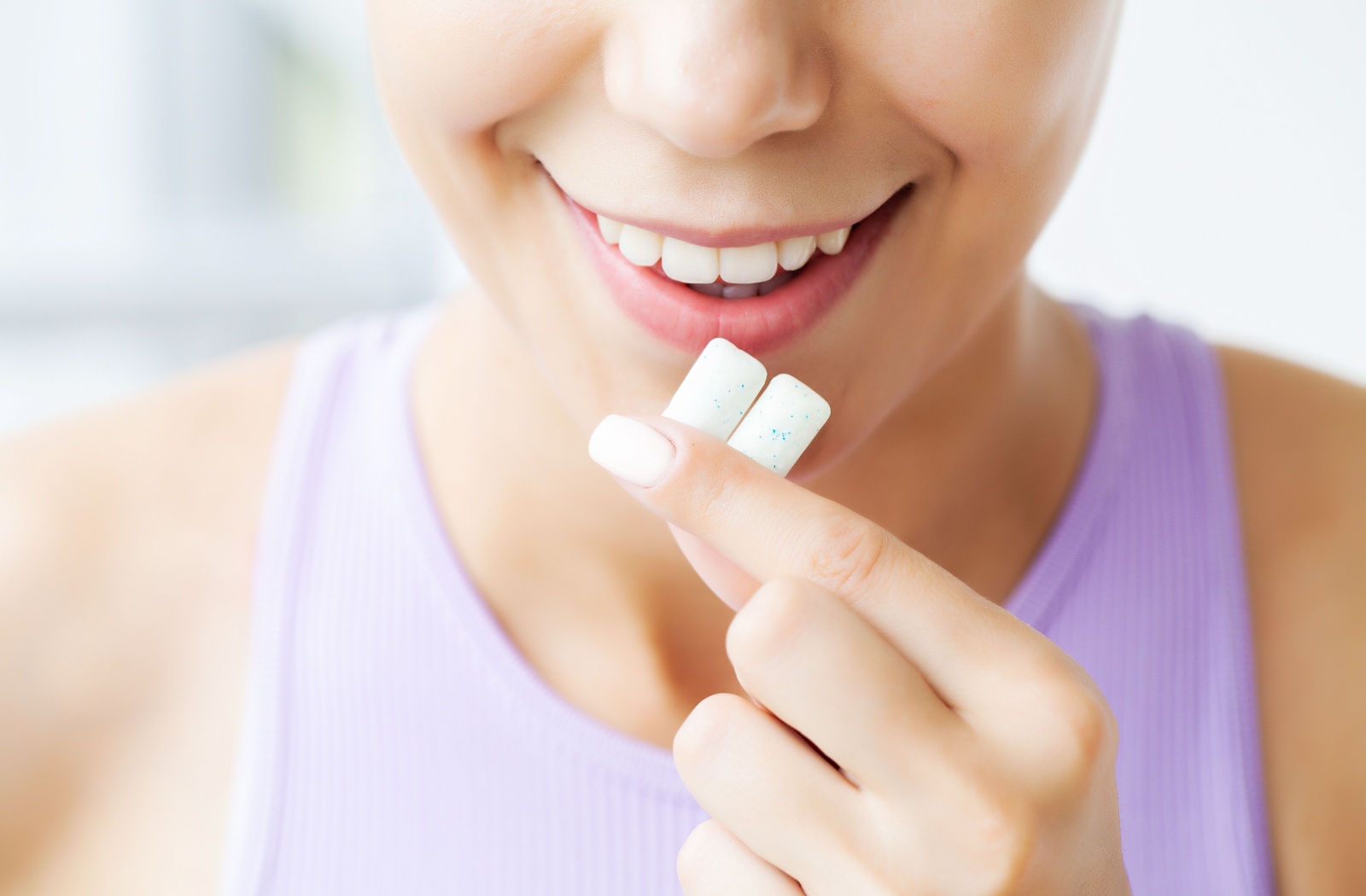 A person holding two pieces of gum in front of their open mouth.
