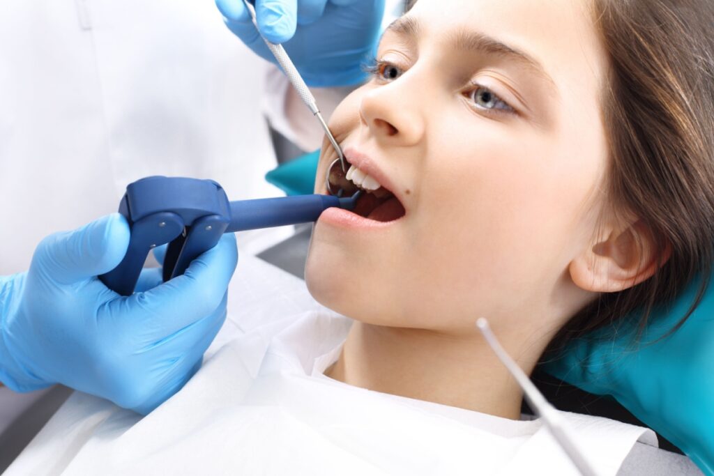 Teen girl having her teeth rinsed at the dentist.